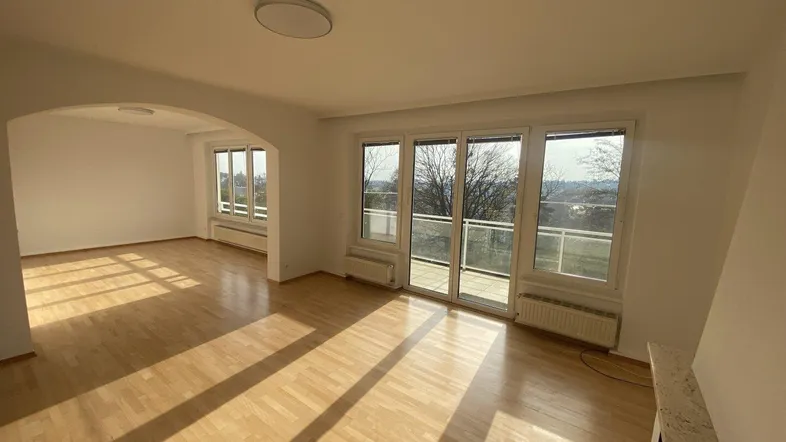 Helles Wohnzimmer mit Parkettboden, Kamin und Zugang zu einem sonnigen Balkon.