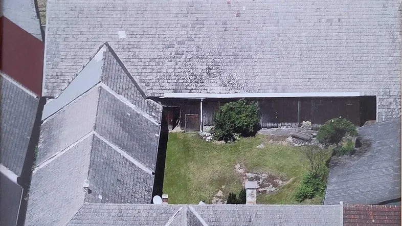 Luftaufnahme des Anwesens mit mehreren Gebäuden, Innenhof und umliegenden Grünflächen.