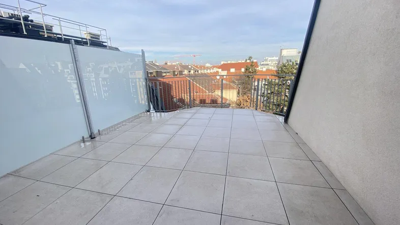 Geräumige Dachterrasse mit Fliesenboden und Blick über die Stadtlandschaft.