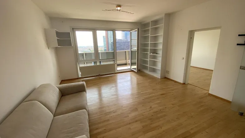 Geräumiges Wohnzimmer mit Parkettboden, Einbauregalen und viel Tageslicht.