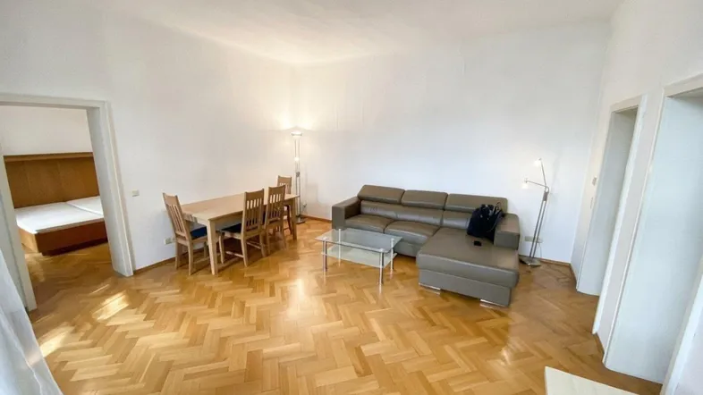 Geräumiger Wohn-Essbereich mit hellem Parkettboden, bequemer Couch und Esstisch für mehrere Personen.