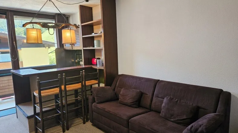 Gemütliches Wohnzimmer mit Sofa, Barbereich und Blick ins Grüne.