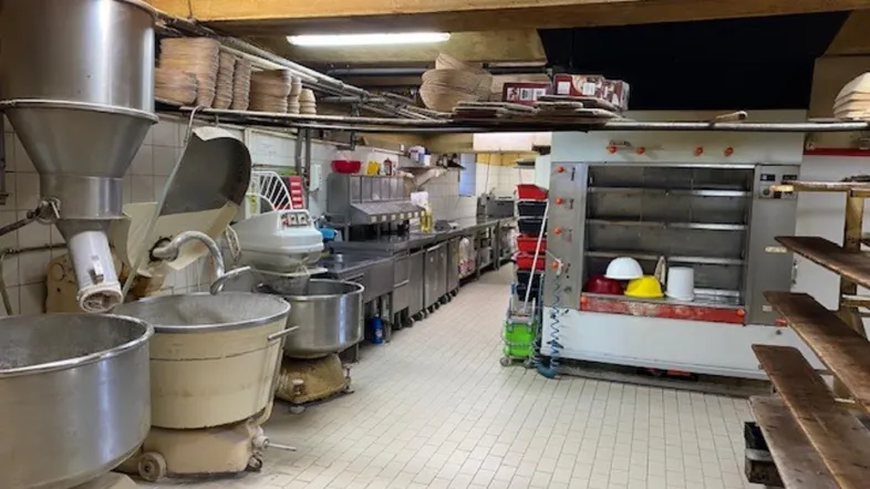 Große Industrieküche mit professionellen Backöfen, Mischmaschinen und Edelstahlarbeitsflächen, ideal für eine Bäckerei.