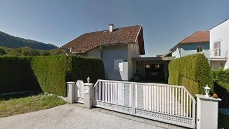 Einfamilienhaus mit gepflegtem Vorgarten, Einfahrt und Carport unter einem Satteldach.