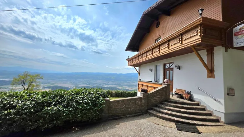 Traditionelles Gebäude mit Holzbalkonen und weitem Blick über die Landschaft unter blauem Himmel.