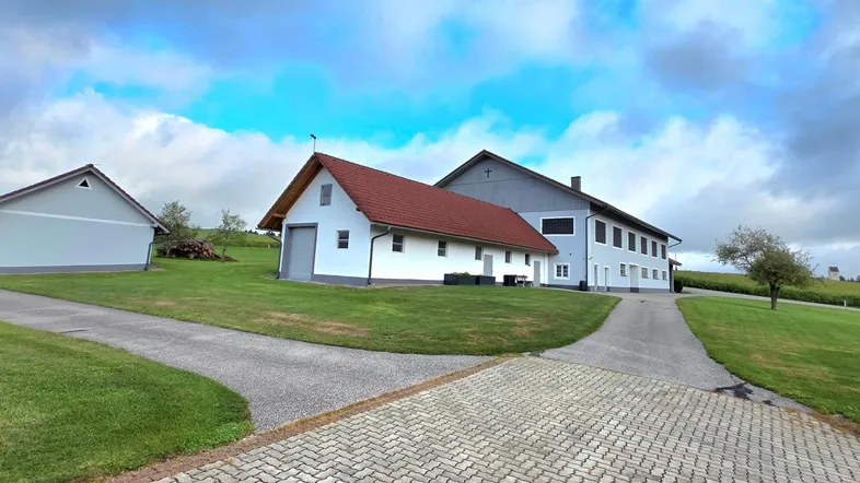 Mehrere Gebäude auf einem weitläufigen Grundstück mit Zufahrtswegen und grünen Rasenflächen unter bewölktem Himmel.