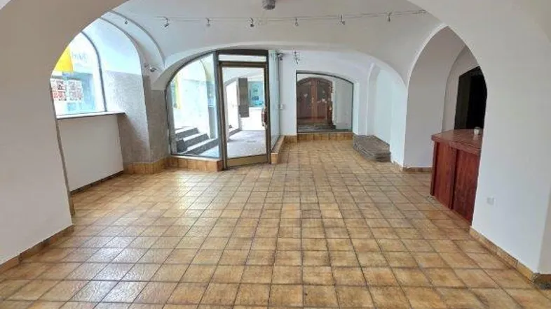 Geräumiger Innenraum mit Gewölbedecken, Fliesenboden und einem Eingangsbereich mit Glasfront.