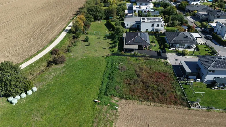 Luftaufnahme eines Wohngebiets neben landwirtschaftlichen Feldern mit mehreren Häusern und Grundstücken.