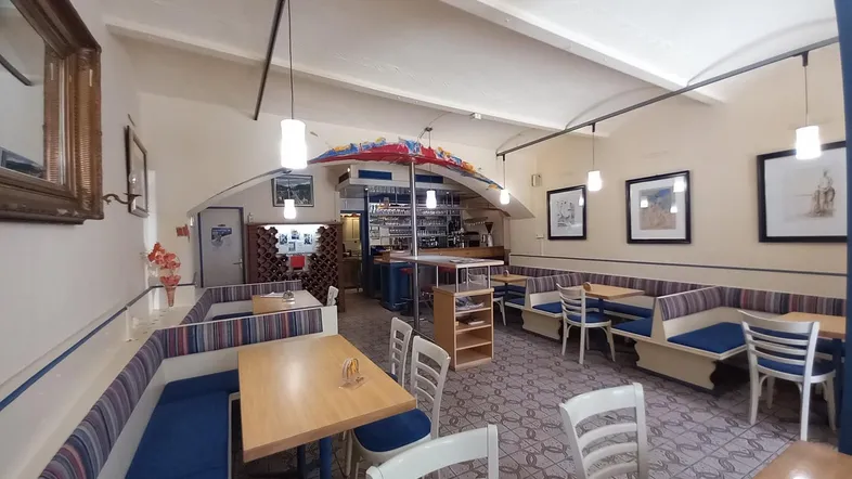 Geräumiger Restaurantbereich mit gemütlichen Sitzbänken, Holztischen und einer Bar im Hintergrund.