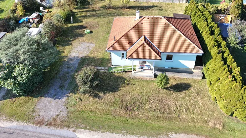 Luftaufnahme eines Einfamilienhauses mit großem Garten und gepflegter Hecke.