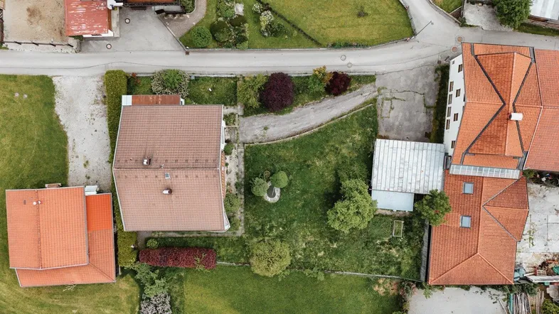 Luftaufnahme eines Wohngebiets mit Häusern, Gärten und Straßen in ländlicher Umgebung.