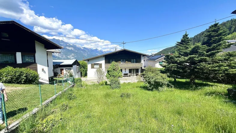 Großer, gepflegter Gartenbereich mit Rasenfläche und Blick auf das Haus und die Berge.