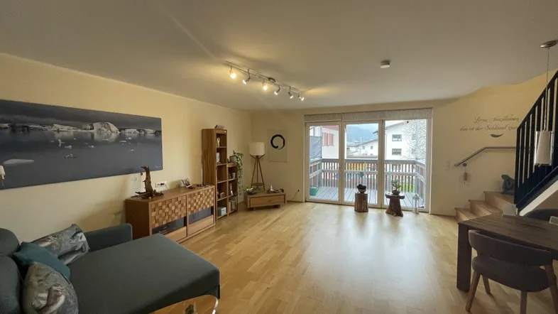 Heller Wohn-Essbereich mit Holzboden, gemütlicher Sitzecke und Blick auf den Außenbereich.