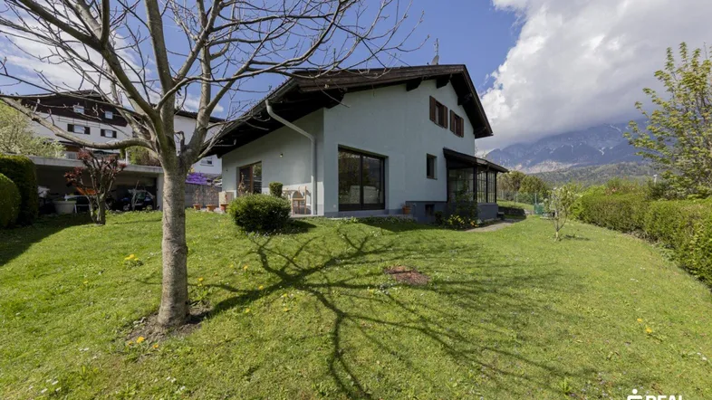Großzügiger Gartenbereich mit Rasenfläche und Baumbestand vor dem Haus mit Bergblick.