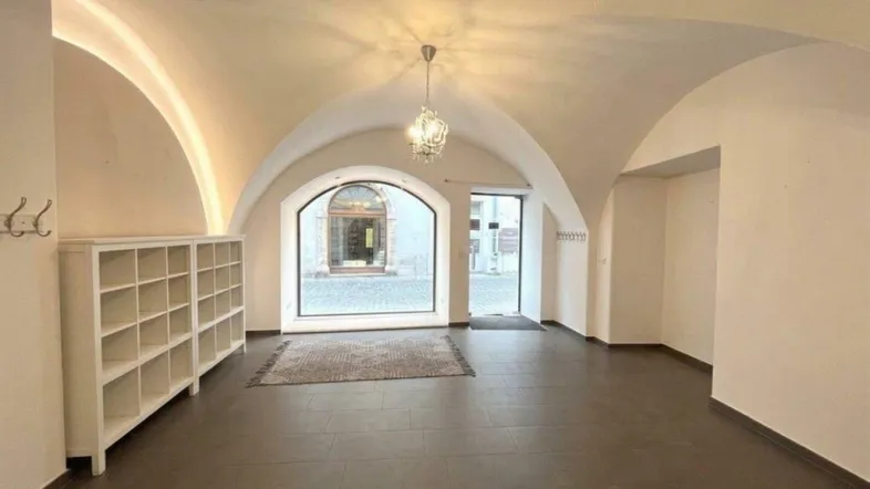 Großer Raum mit Gewölbedecke, großen Fenstern und dunklem Fliesenboden, ideal für ein Büro.