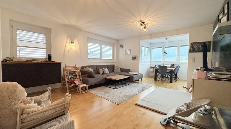 Geräumiger Wohn-Essbereich mit hellem Parkettboden, gemütlichem Sofa und Essbereich im Erker mit Weitblick.