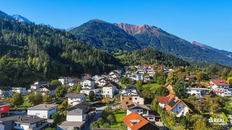 Panoramablick auf ein malerisches Dorf in den Bergen mit grünen Wäldern und klarem Himmel.
