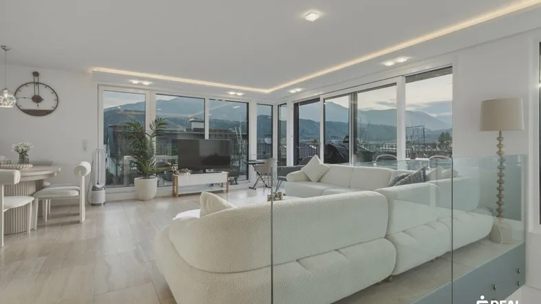 Helles, offenes Wohn-Esszimmer mit großen Fenstern, Bergblick und moderner Einrichtung.