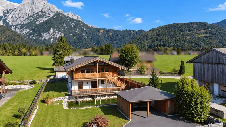 Traditionelles Holzhaus im alpinen Stil mit Bergblick und gepflegtem Gartenbereich.