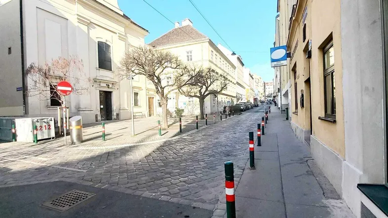Kopfsteingepflasterte Straße mit historischen Gebäuden und sonnigem Wetter in der Stadt.