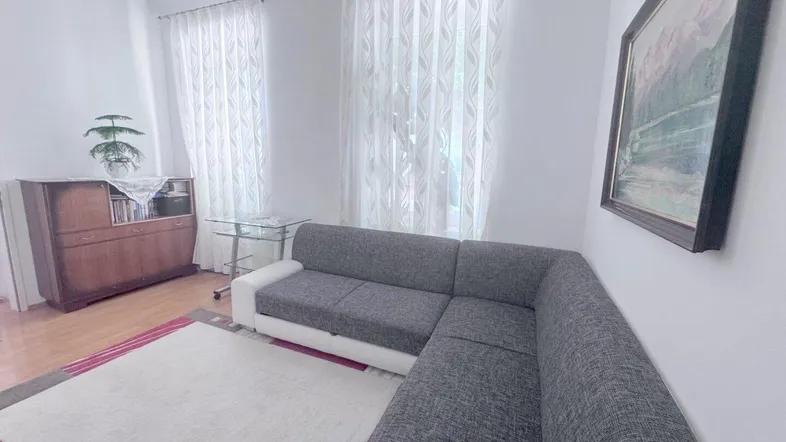 Helles Wohnzimmer mit modernem Ecksofa, Teppich und einem antiken Sideboard.