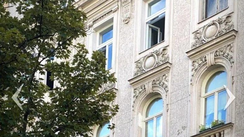Historische Fassade eines Altbaus mit reich verzierten Fenstern und Stuckelementen.