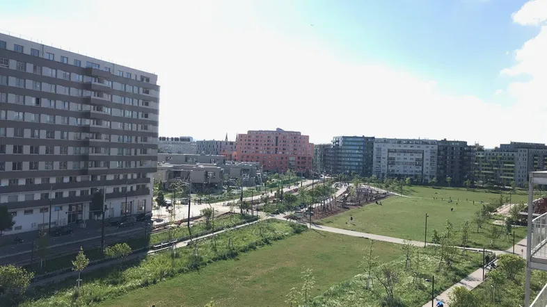 Weitläufige Grünfläche mit Spielplatz und modernen Wohngebäuden im Hintergrund.
