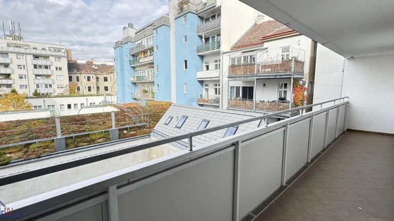 Geräumiger Balkon mit Blick auf die umliegenden Gebäude und begrünte Dächer in der Stadt.