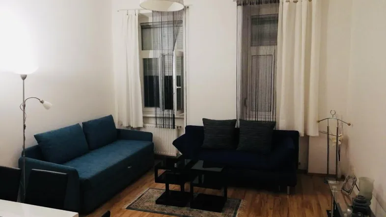 Gemütliches Wohnzimmer mit zwei Sofas, Holzboden und hellen Wänden, ideal zum Entspannen.