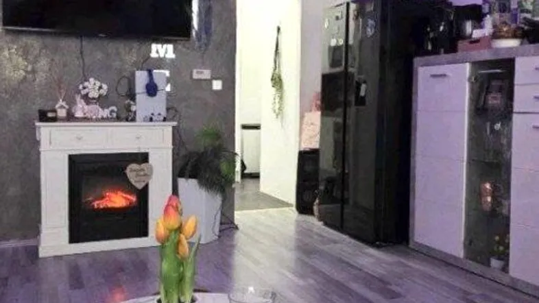 Modernes Wohnzimmer mit Wandfernseher, Elektrokamin, Sofa und dekorativer LED-Beleuchtung.