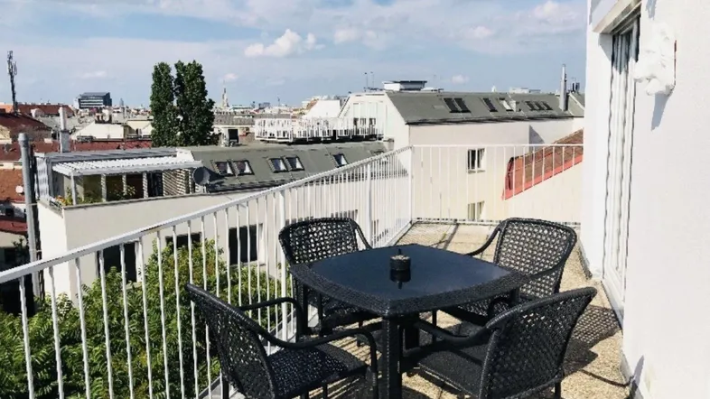 Möblierte Dachterrasse mit Esstisch und Stühlen, bietet einen weiten Blick über die Stadt.