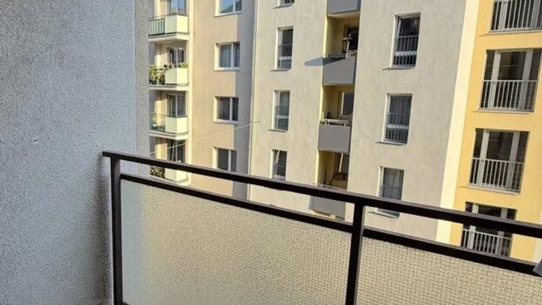 Heller Balkon mit Blick auf die umliegenden Wohngebäude unter blauem Himmel.