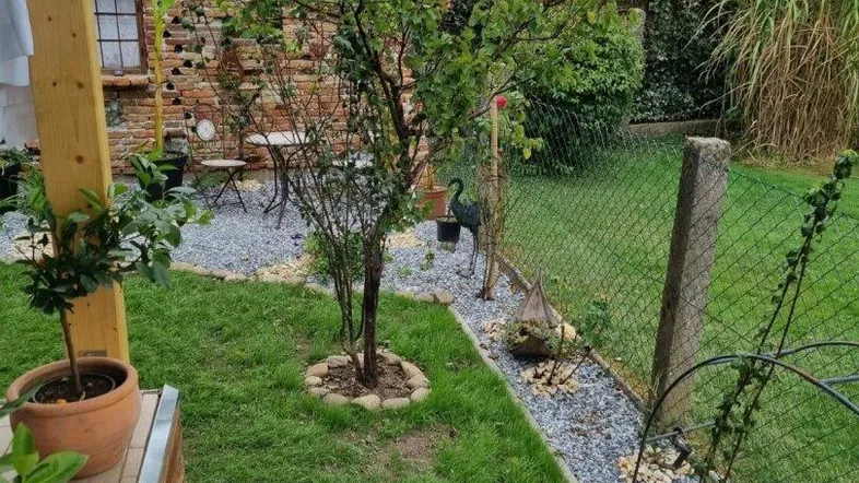 Gepflegter Gartenbereich mit Kieswegen, Rasenfläche und einer charmanten Sitzecke an einer alten Ziegelmauer.