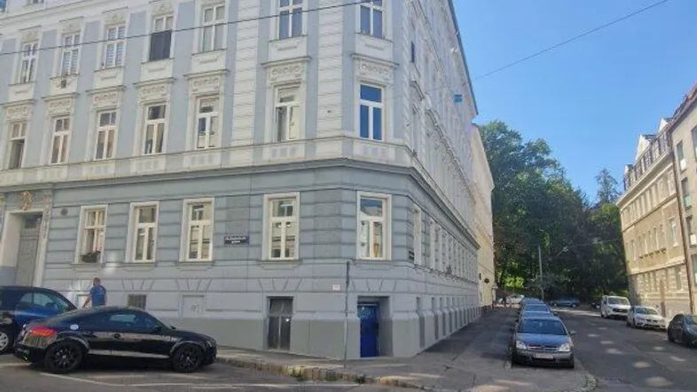 Eckgebäude mit klassischer Architektur und hellblauer Fassade an einem sonnigen Tag.