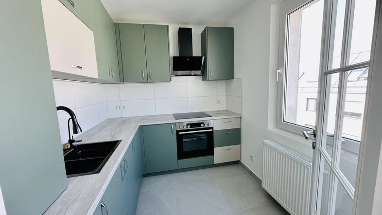 Moderne Küche mit hellgrünen Schränken, integrierten Geräten und einem großen Fenster für viel Tageslicht.