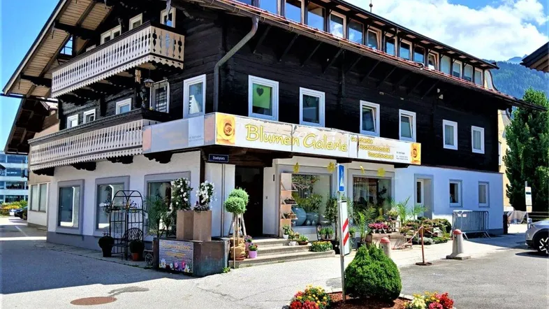 Traditionelles Gebäude mit dunkler Holzfassade, verzierten Balkonen und einem Blumengeschäft im Erdgeschoss.