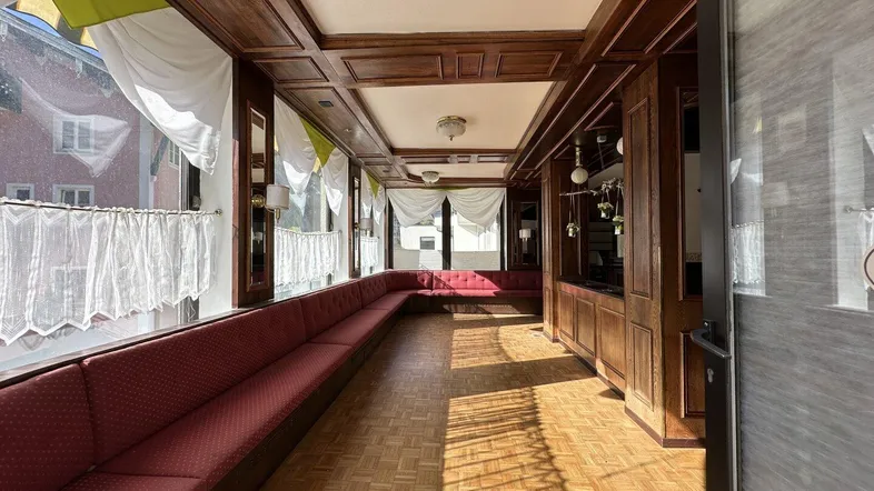 Geräumiger kommerzieller Loungebereich mit Holztäfelung, langen Sitzbänken und Parkettboden.
