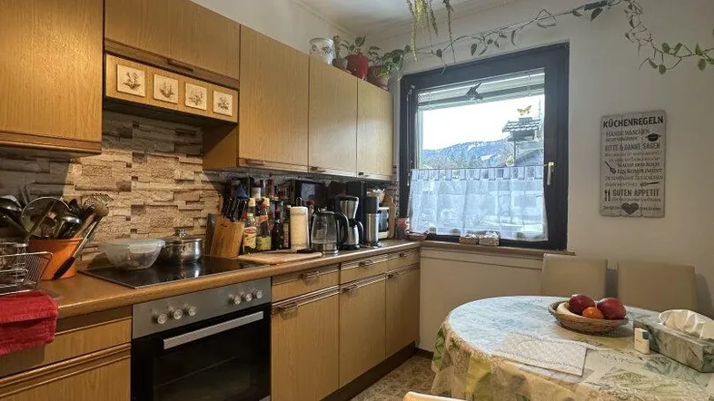 Traditionelle Einbauküche mit Essbereich, Fliesenboden und Blick auf die Berge durch das Fenster.