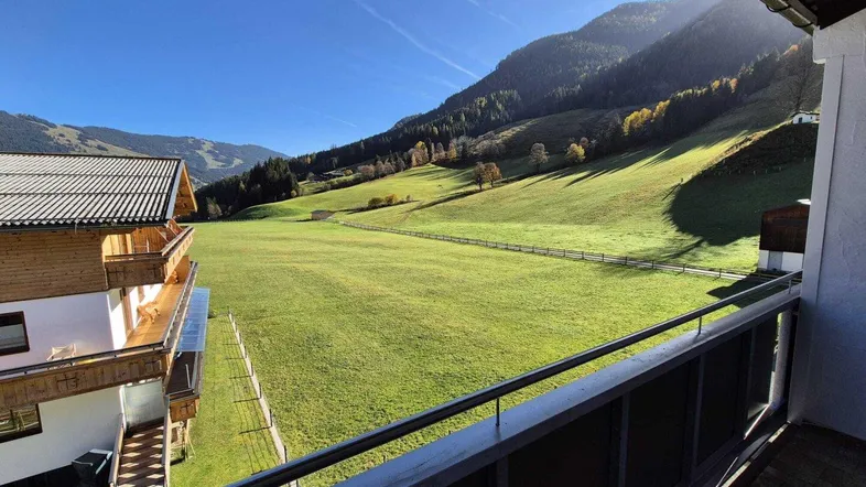 Sonniger Balkon mit weitem Blick über grüne Wiesen und die umliegenden Berge.