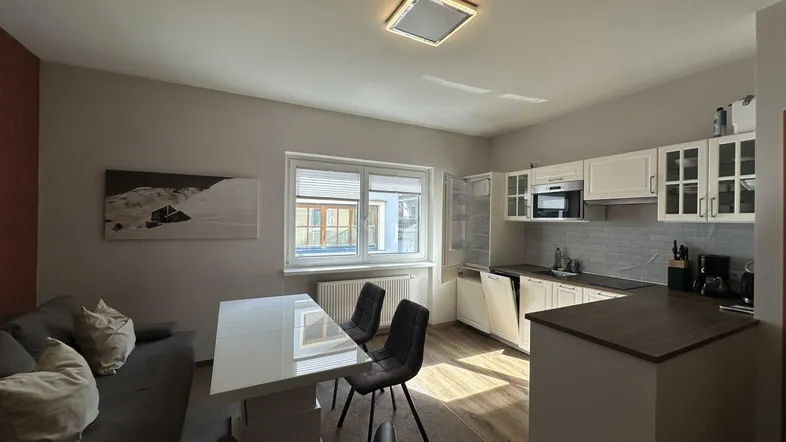 Heller offener Wohn-Essbereich mit integrierter Küche, Laminatboden und Fenster.