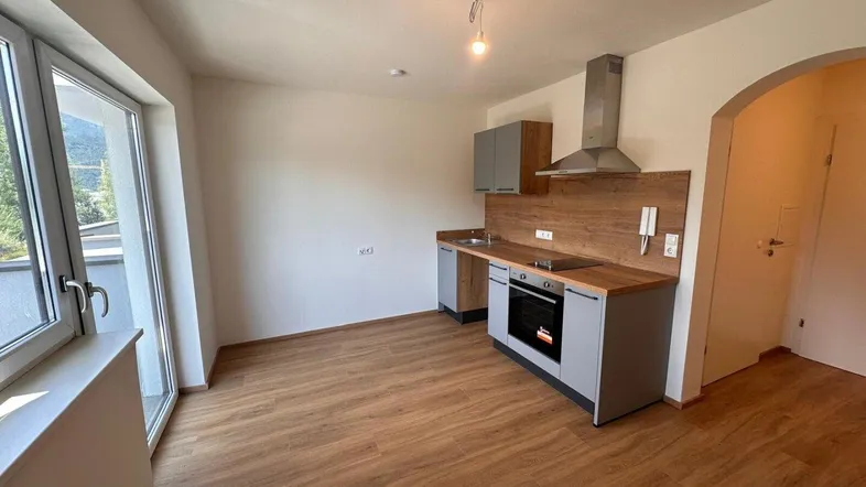 Moderne Küchenzeile in einem hellen Raum mit Holzboden und Zugang zu einem Balkon.