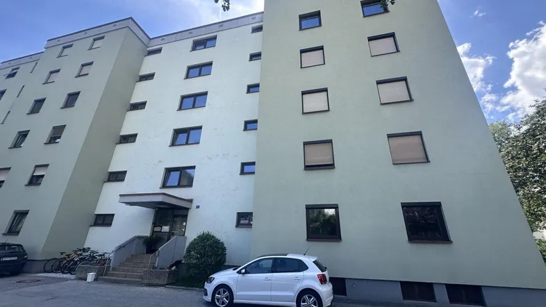 Ansicht eines hohen Wohngebäudes mit hellgrüner Fassade und vielen Fenstern.