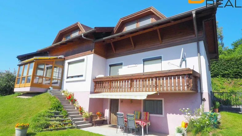 Charmantes Haus mit Wintergarten, Terrasse und Balkon, umgeben von einem gepflegten Garten.