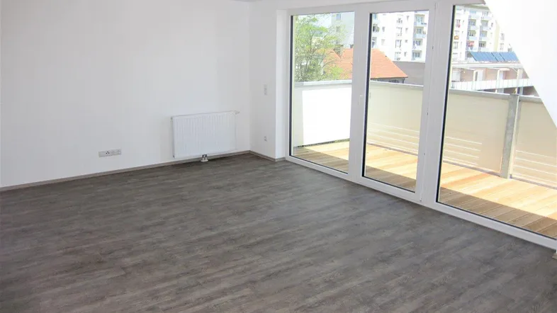 Helles Zimmer mit großen Fenstern, Zugang zum Balkon und modernem Laminatboden.