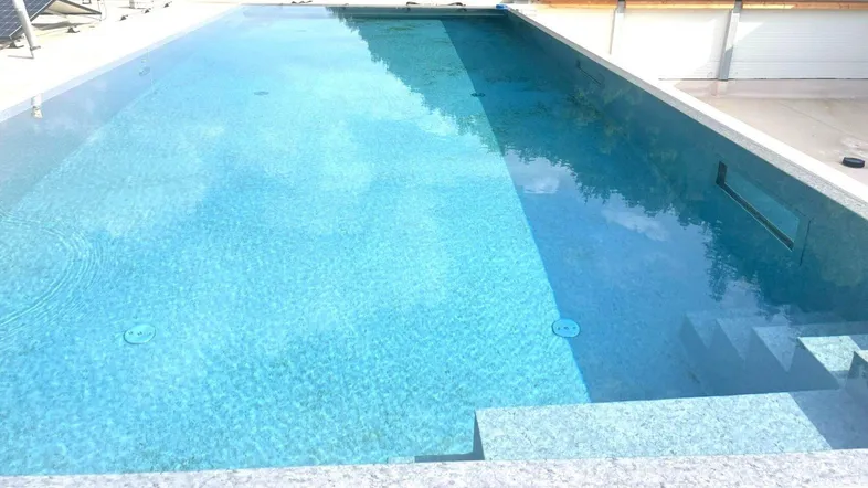 Großer Außenpool auf dem Dach mit klarem Wasser und umliegenden Fliesen.
