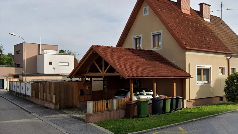Einfamilienhaus mit Carport und Vorgarten in einer ruhigen Wohngegend mit Satteldach.