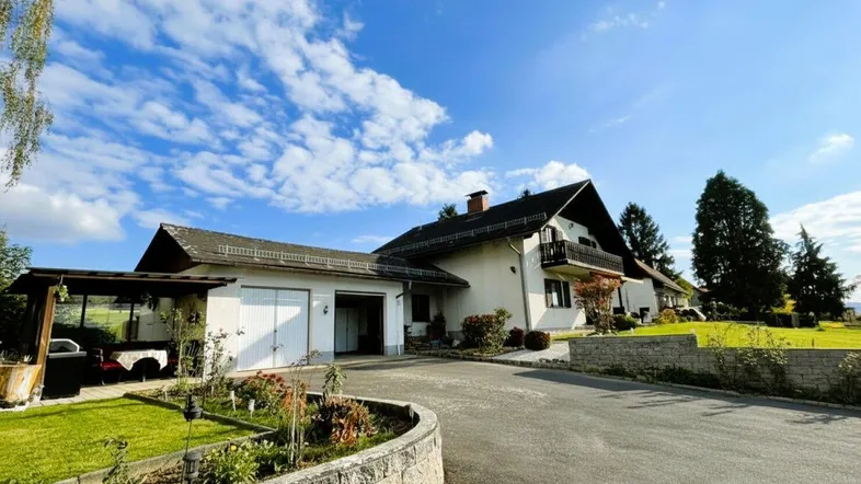 Ansicht des Hauses mit Doppelgarage, gepflegter Auffahrt und umgebendem Grünbereich.