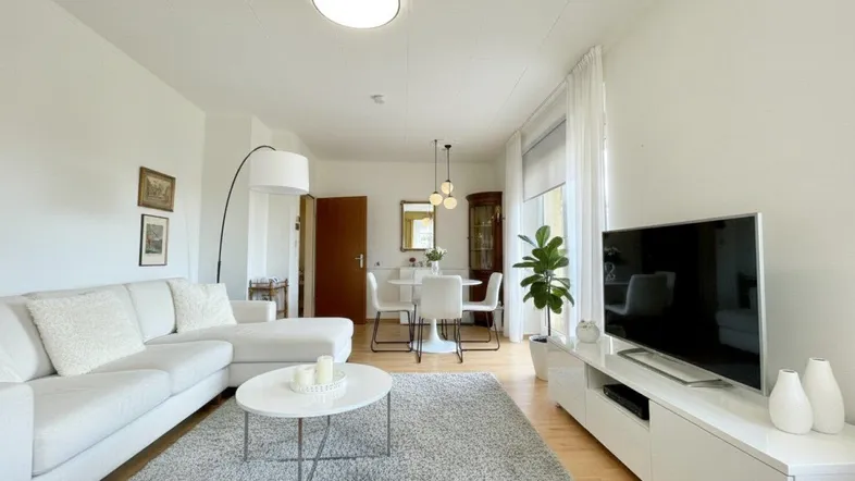 Helles Wohn- und Esszimmer mit Parkettboden, weißem Sofa und modernem Esstisch.