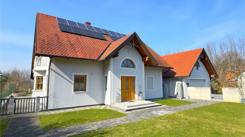 Frontansicht des gepflegten Einfamilienhauses mit Photovoltaikanlage auf dem Dach und grünem Vorgarten.