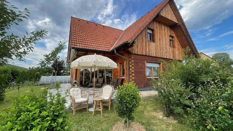 Charmantes Holzhaus mit Satteldach, gepflegtem Garten und gemütlicher Terrasse mit Sitzgelegenheiten.